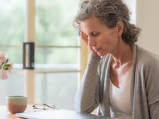 Woman with her head in her hand at a closed laptop