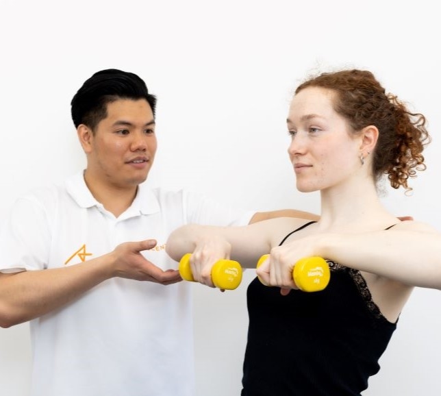 An Ascenti physiotherapist helping patient lift small hand weights