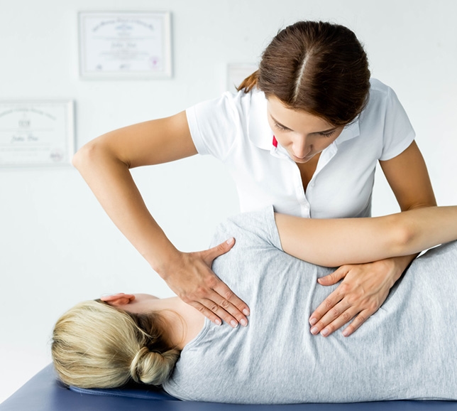 Woman lying down having her back examined by an osteopath