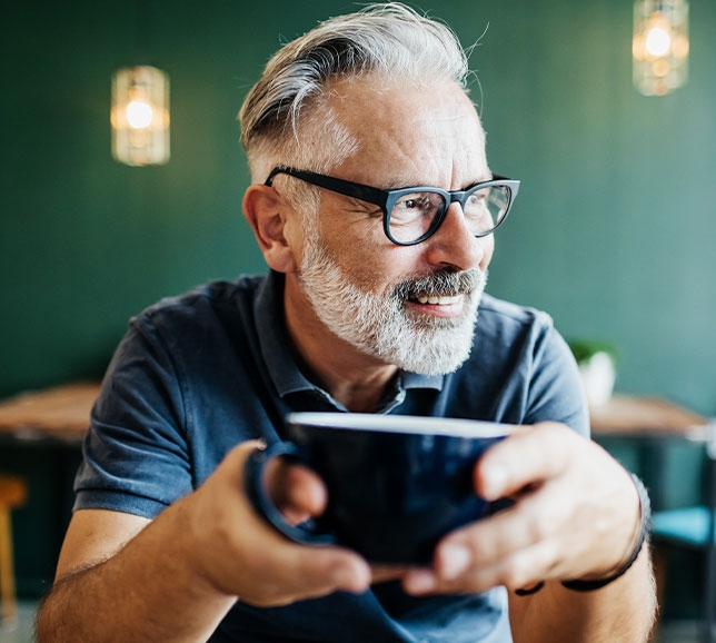 Man wearing glasses and holding a coffee mug