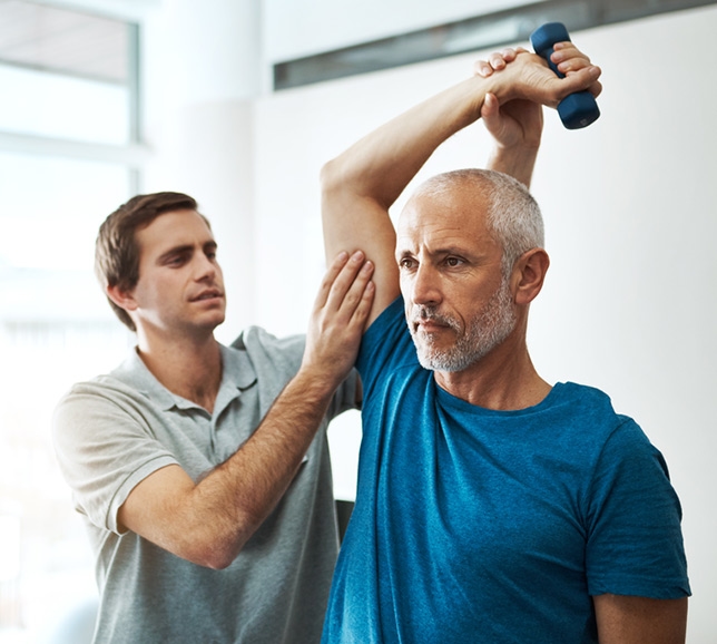 Man holding a weight and stretching his arm, guided by a physiotherapist