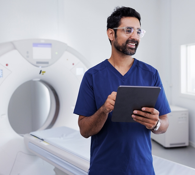 Medical professional stood beside a CT scanner