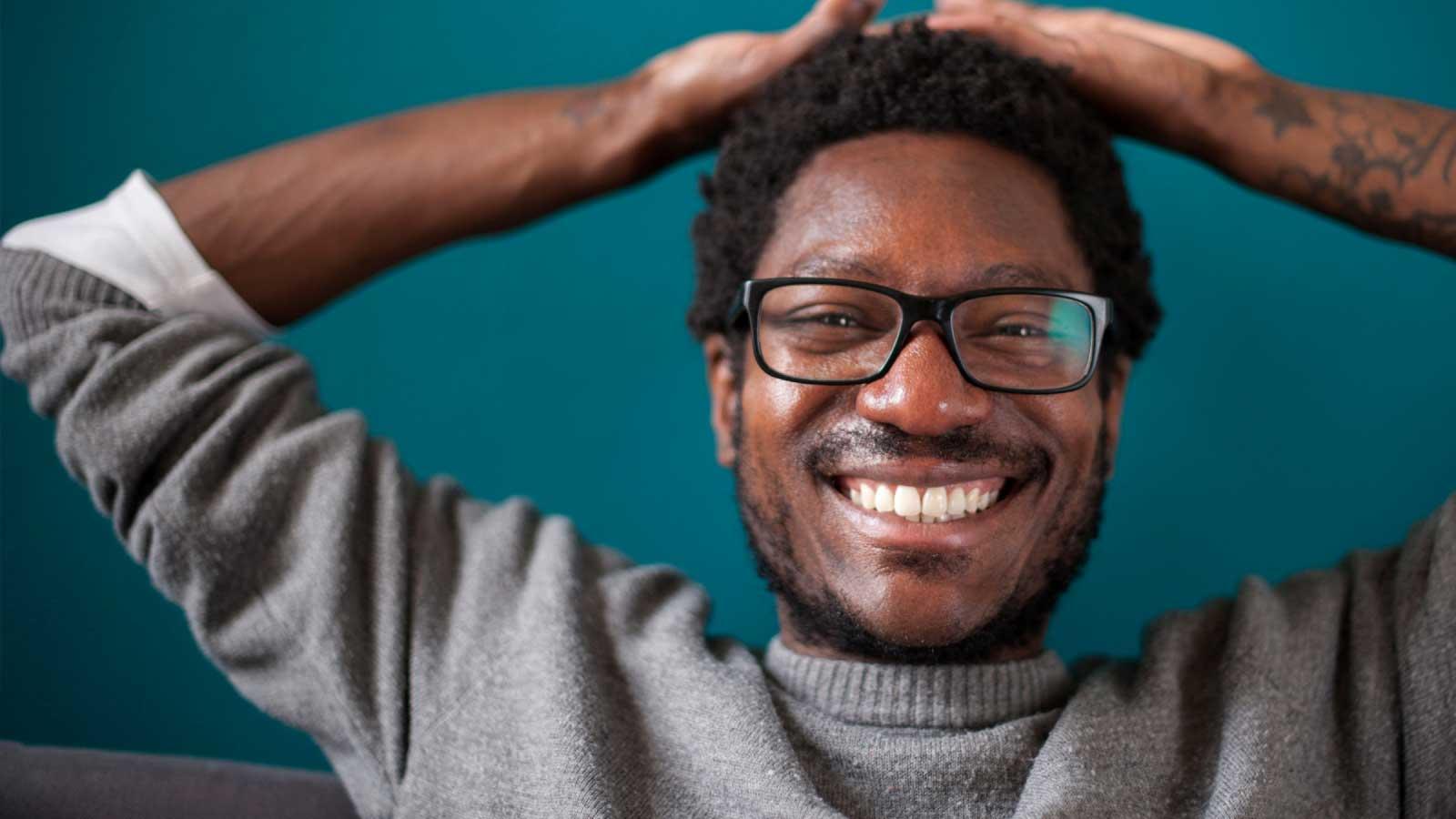 Man smiling with hands on head