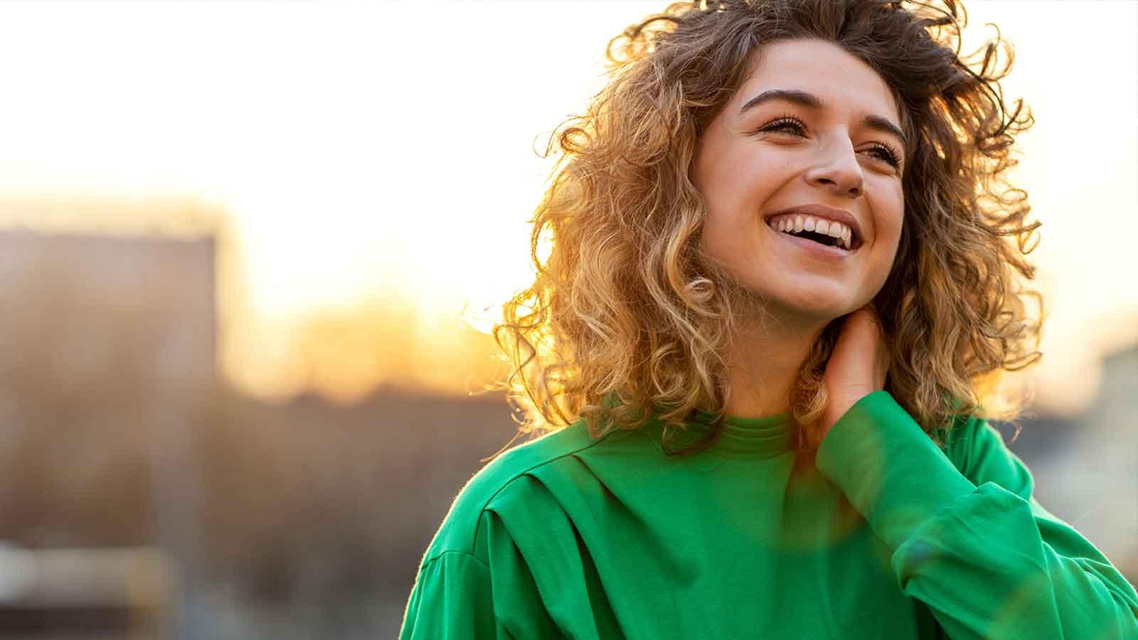 Lady smiling outdoors with the sun setting behind her