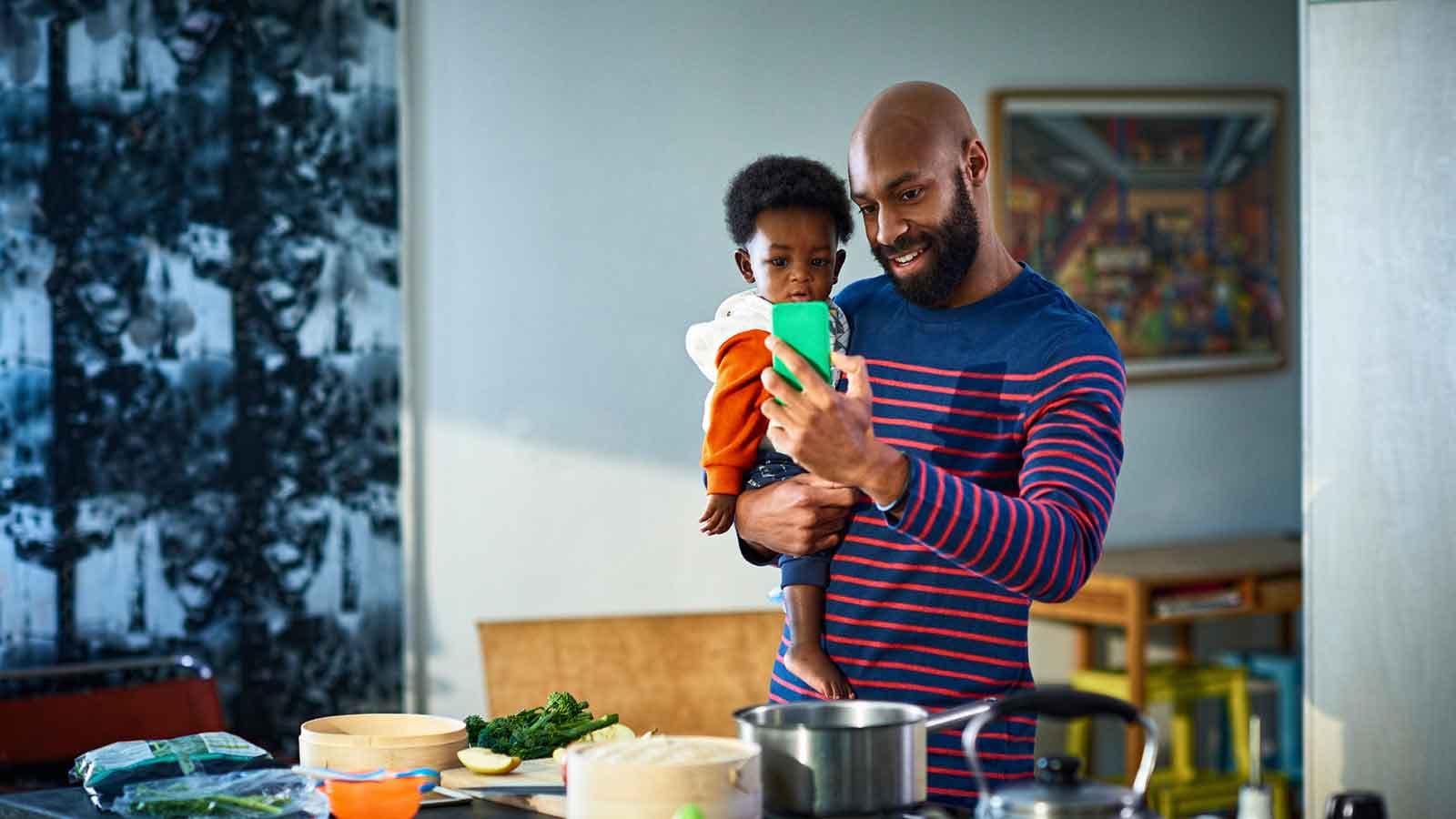 Father standing, holding baby son whilst having a GP video call