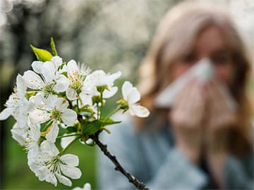 Woman sneezing outside due to pollen