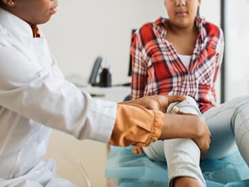 Teenager having knee examined by a physiotherapist