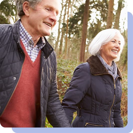 Happy couple holding hands walking in woods