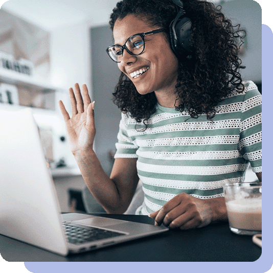 Woman wearing headphones and waving at her laptop screen