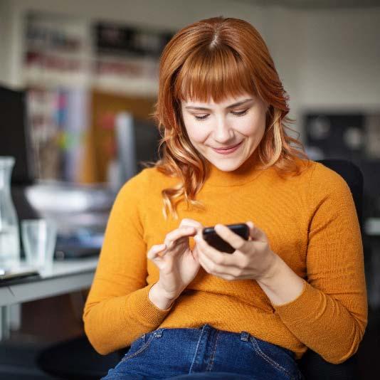 Woman sat at home office desk using her smart phone