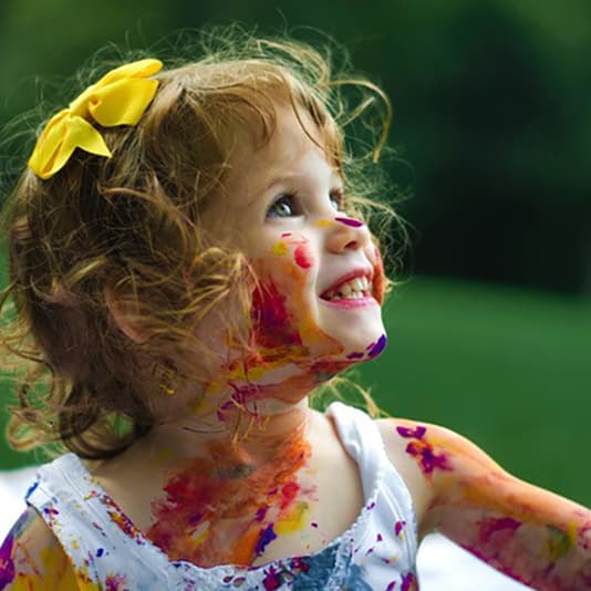 A young girl smiling and covered in face paint