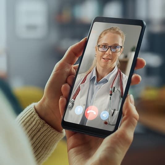 Lady holding phone talking to a doctor via video call