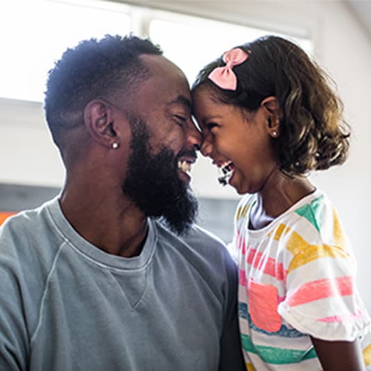 Father and daughter with foreheads together smiling