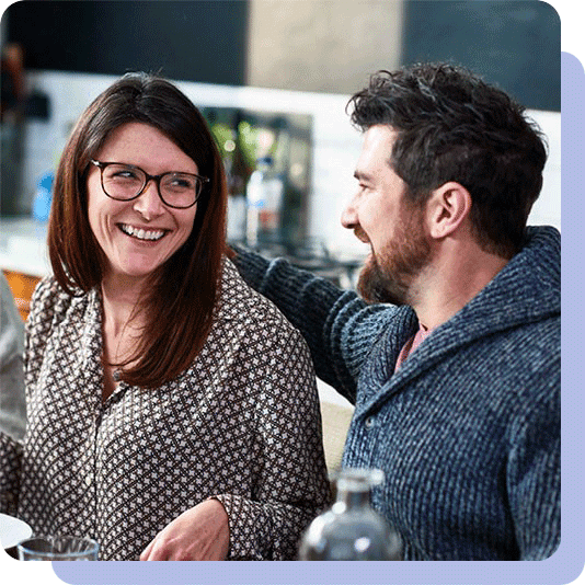 Man with arm around woman's shoulder and smiling at each other