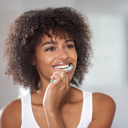 Curly haired lady brushing teeth