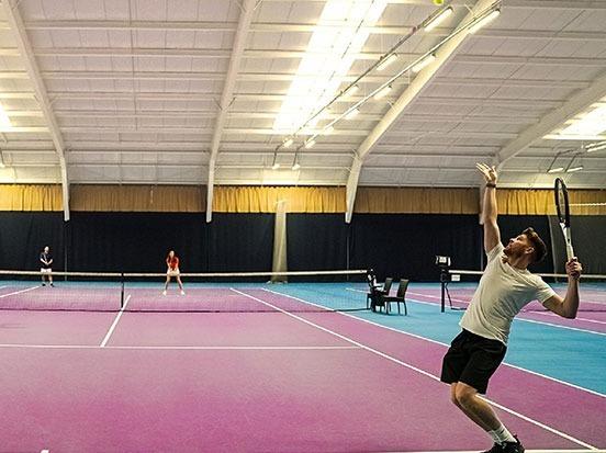 Man playing tennis at David Lloyd tennis court