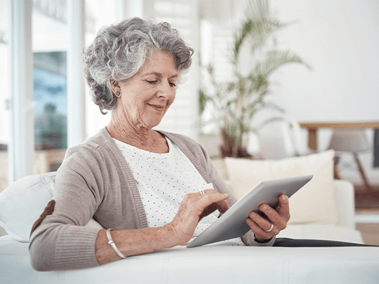 Older white woman looks at a tablet device