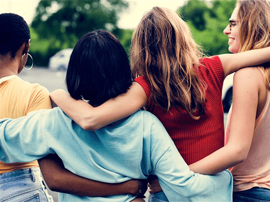 Group of women link arms from behind