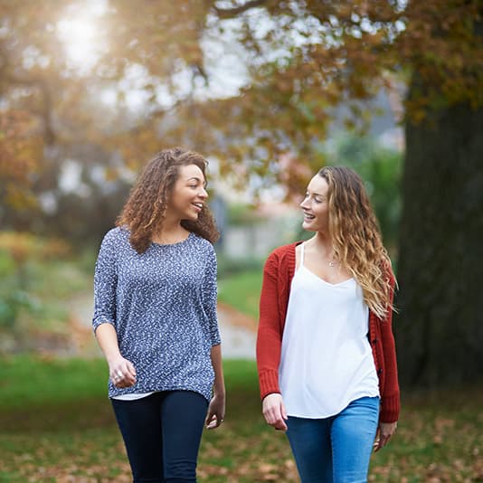 Two women talking and walking in an autumnal park