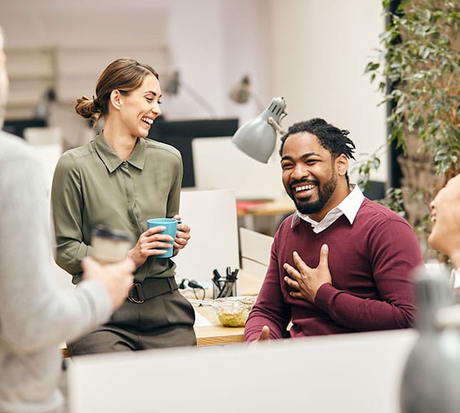 Office workers sat around their desks, laughing and smiling
