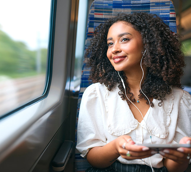 Woman wearing headphones and looking out of train window