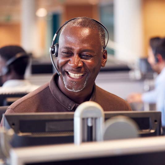 Man wearing headset at a computer and smiling