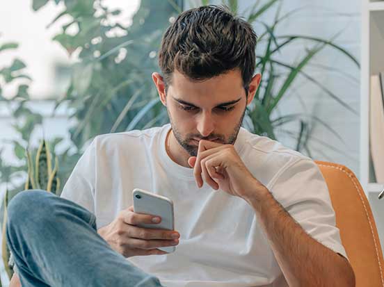 Man feeling anxious researching symptoms online using mobile phone
