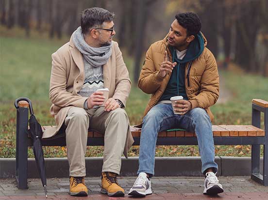 Two men having conversation on bench outside